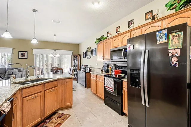 a kitchen with stainless steel appliances granite countertop a refrigerator a sink dishwasher a stove and white cabinets with wooden floor