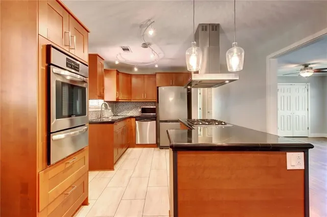 a kitchen with stainless steel appliances granite countertop a stove a sink dishwasher and a refrigerator with wooden floor