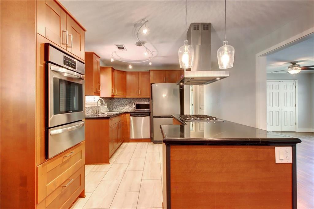 1408 Ruth Avenue Austin, TX 78757 - Photo 10 of 33 a kitchen with stainless steel appliances granite countertop a refrigerator a sink dishwasher a stove and a dining table with wooden floor