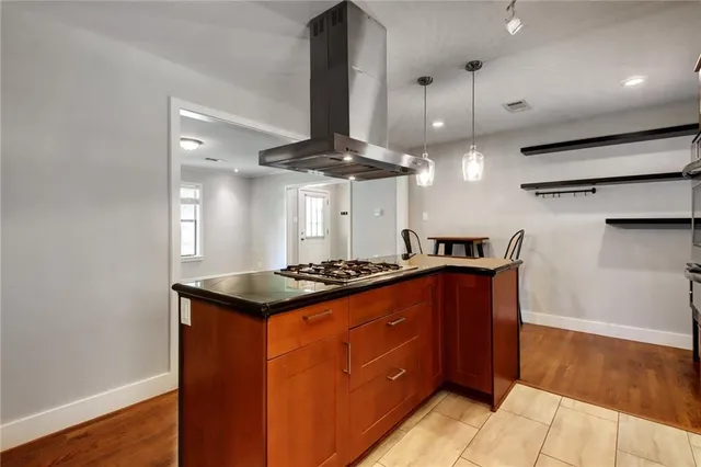 a kitchen with stainless steel appliances granite countertop a refrigerator a sink dishwasher a stove and a dining table with wooden floor