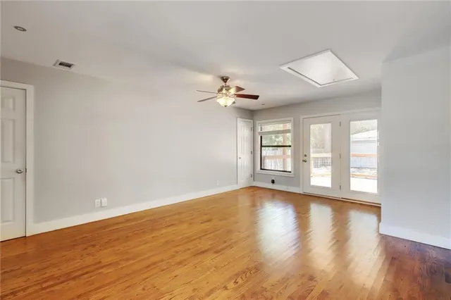 a view of an empty room with wooden floor and a window