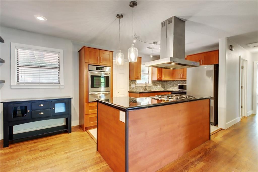 1408 Ruth Avenue Austin, TX 78757 - Photo 7 of 33 a kitchen with stainless steel appliances granite countertop a refrigerator a stove and a sink with wooden floor