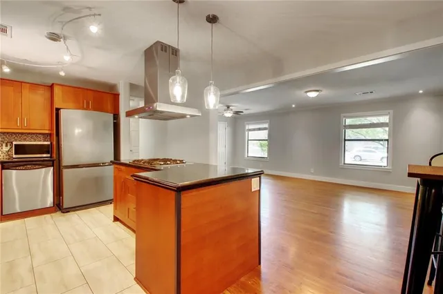 a kitchen with stainless steel appliances granite countertop a refrigerator a stove and a sink with wooden floor