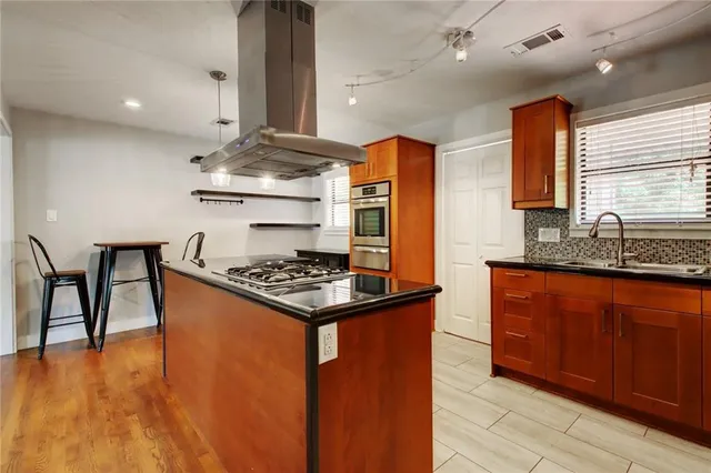 a kitchen with stainless steel appliances granite countertop a refrigerator a sink dishwasher a stove and white countertops with wooden floor