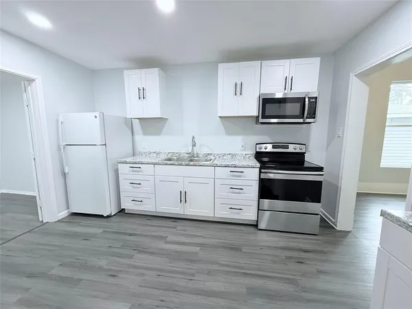 a kitchen with stainless steel appliances a white stove and white cabinets