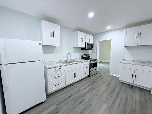 a kitchen with white cabinets white stainless steel appliances and wooden floors