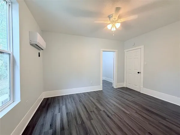 a view of an empty room with wooden floor and a window