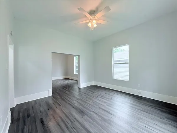 an empty room with wooden floor and windows