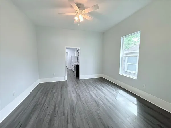 a view of an empty room with wooden floor and a window