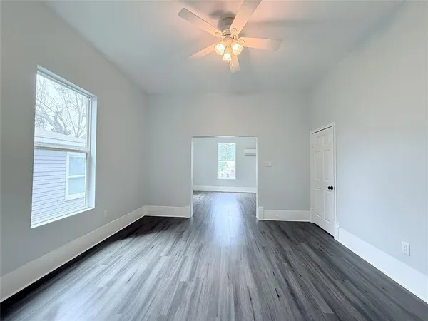 a view of empty room with wooden floor and fan