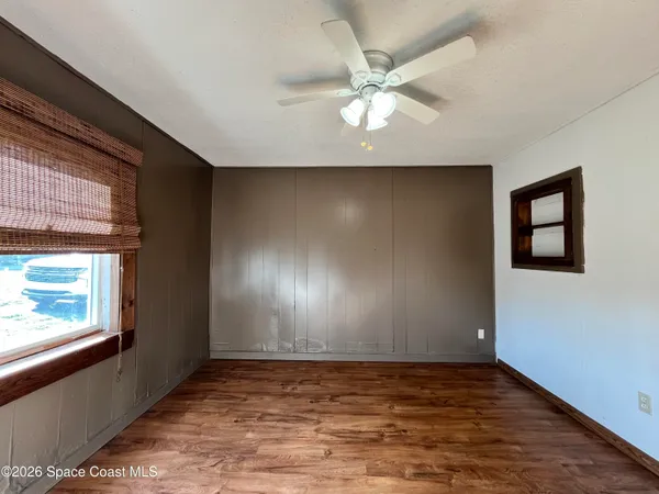 a view of an empty room with window and wooden floor