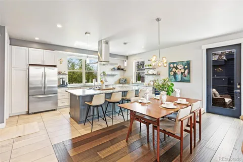 a kitchen with stainless steel appliances kitchen island granite countertop a dining table chairs and white cabinets