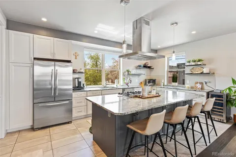 a kitchen with stainless steel appliances granite countertop a sink a stove a refrigerator and island with wooden floor