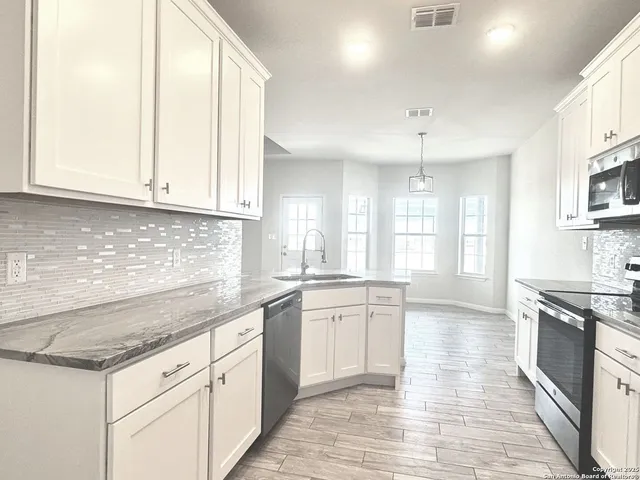 a large kitchen with granite countertop a stove sink and cabinets