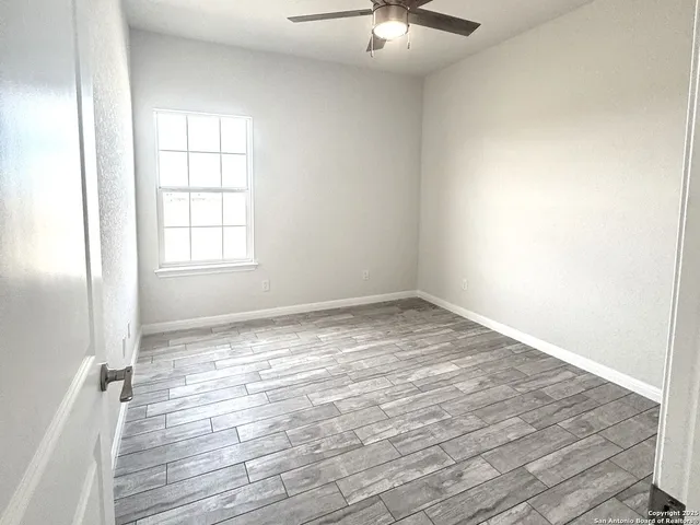 an empty room with wooden floor fan and windows