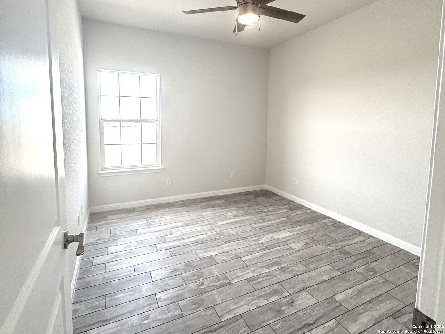 14329 Wisdom Road Atascosa, TX 78002 - Photo 6 of 18 an empty room with wooden floor fan and windows