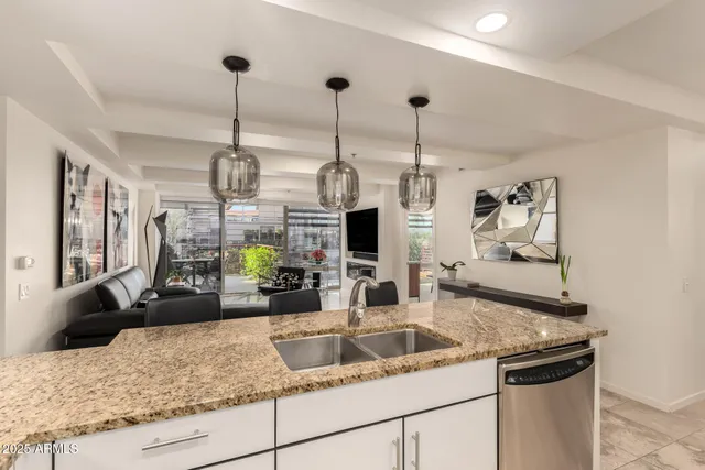 a kitchen with granite countertop a sink a counter top space and living room view