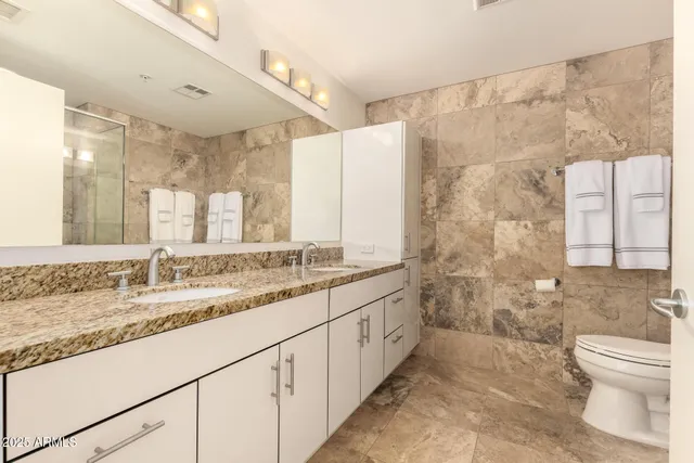 a bathroom with a granite countertop sink a toilet a mirror and shower