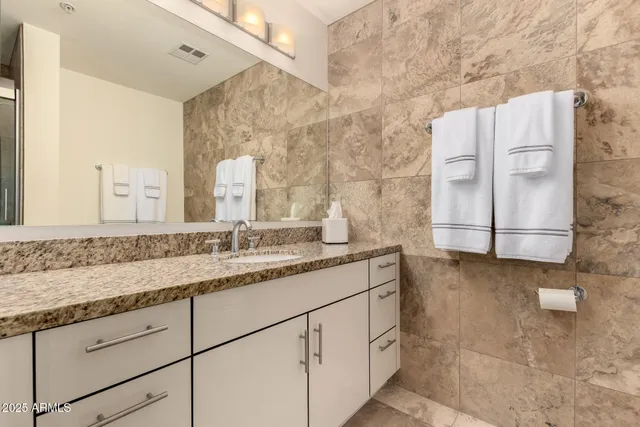 a bathroom with a granite countertop sink a mirror and a shower