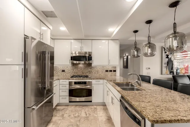 a large kitchen with stainless steel appliances granite countertop a sink stove and refrigerator