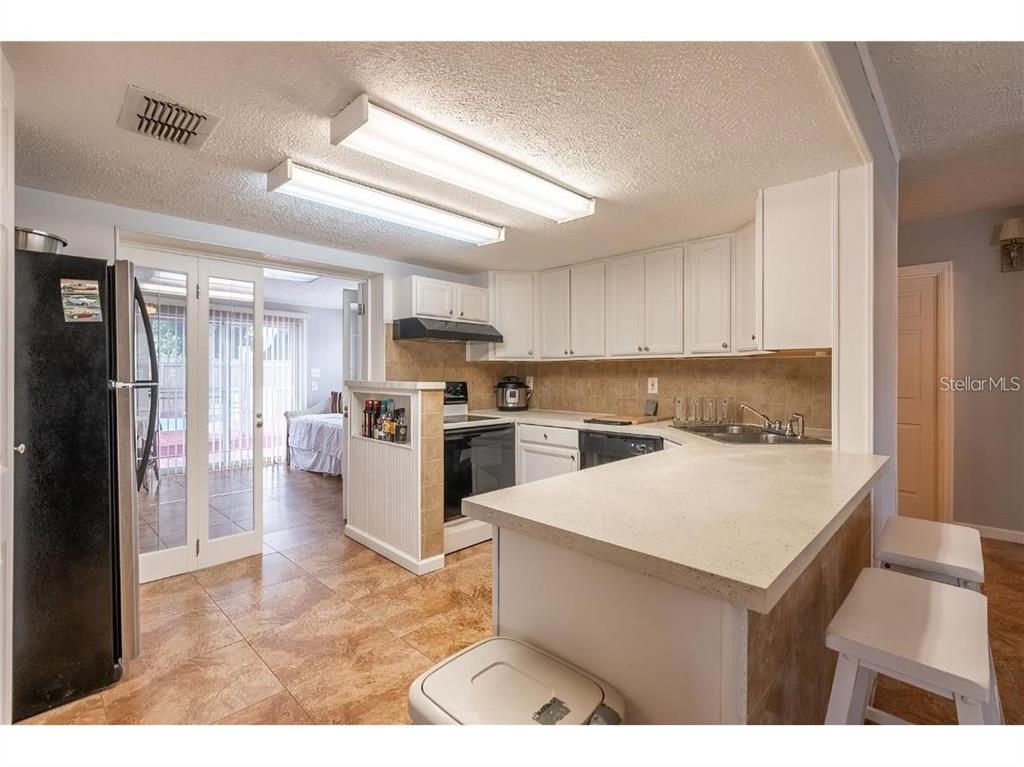5334 Dartmouth Road New Port Richey, FL 34652 - Photo 2 of 13 a kitchen with a sink a stove a refrigerator and white cabinets