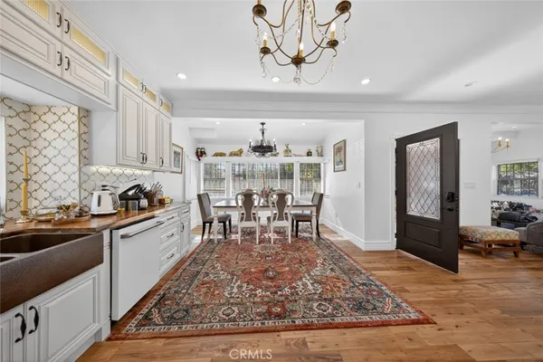 a kitchen with stainless steel appliances granite countertop a sink dishwasher a stove a refrigerator dining table and chairs with wooden floor