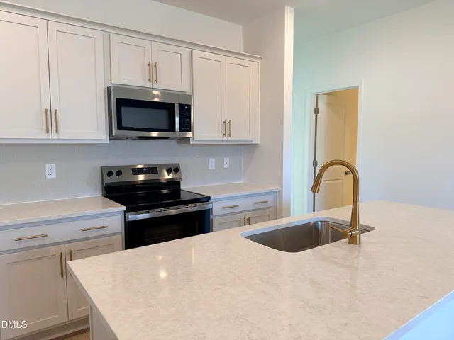 a kitchen with stainless steel appliances granite countertop a sink a stove top oven and white cabinets