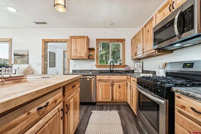 a kitchen with stainless steel appliances granite countertop a stove top oven a sink dishwasher and cabinets with wooden floor