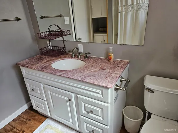 a bathroom with a granite countertop toilet sink and mirror