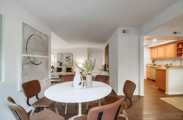 a living room with furniture potted plant and kitchen view