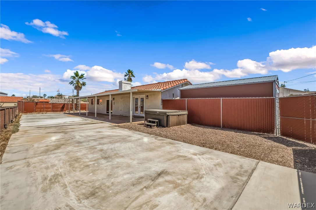 4088 Mercer Road Bullhead City, AZ 86429 - Photo 29 of 35 Expansive concrete patio area featuring a hot tub, gravel landscaping, and a covered back patio with support columns