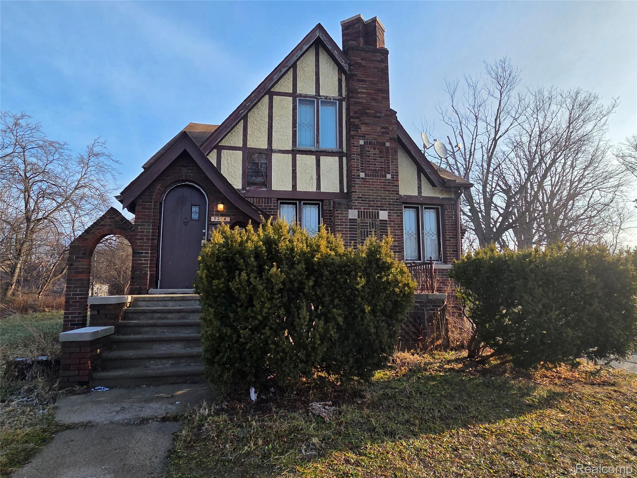 Tudor home featuring stucco siding, a chimney, and brick siding