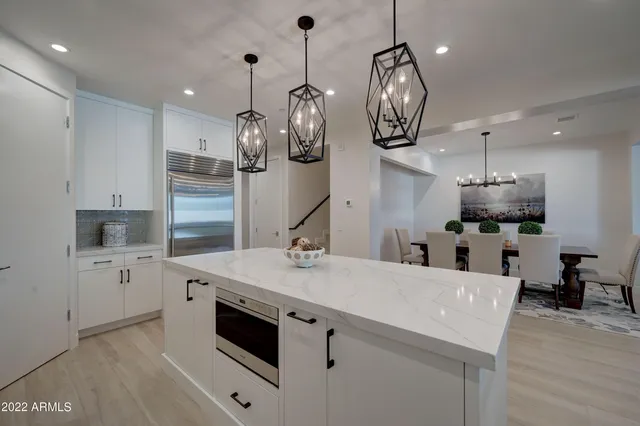 a kitchen with stainless steel appliances granite countertop a sink a stove top oven a clock and cabinets