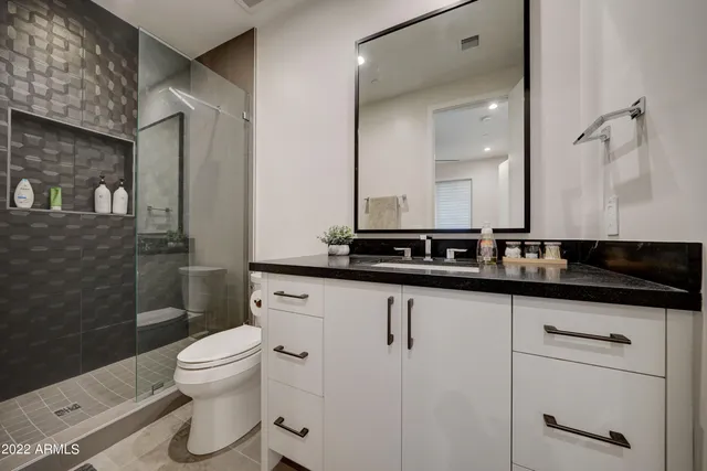 a bathroom with a sink a toilet a mirror and shower