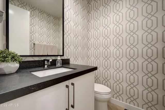 a bathroom with a granite countertop sink and a toilet