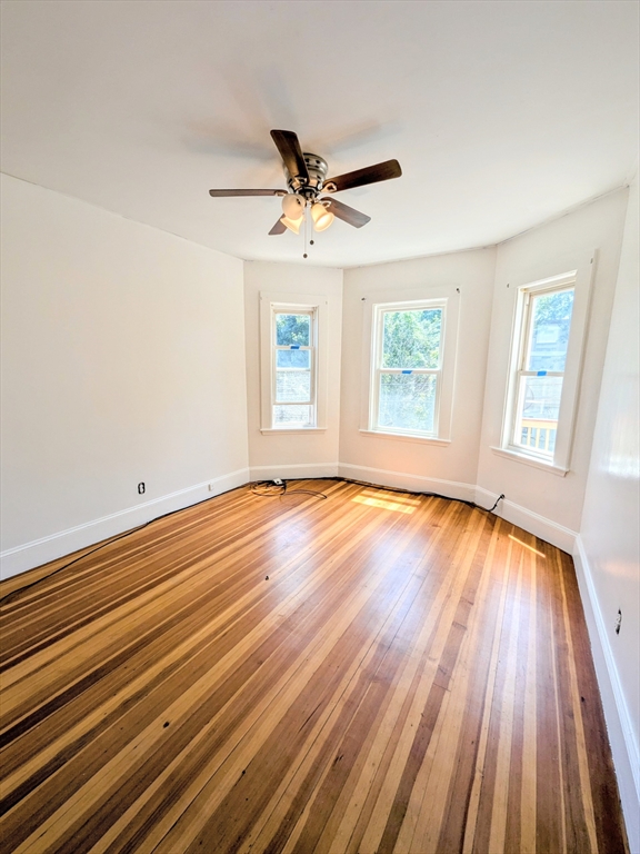84 Bailey Street Boston, MA 02124 - Photo 11 of 11 an empty room with wooden floor chandelier fan and windows