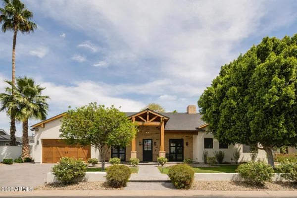 a front view of a house with garden space and trees