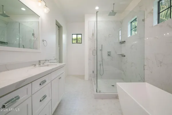 a bathroom with a bathtub shower sink vanity and mirror
