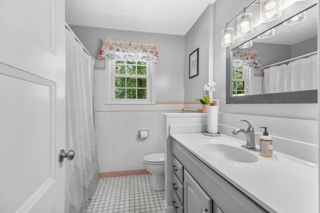 a bathroom with a sink a toilet a window and shower