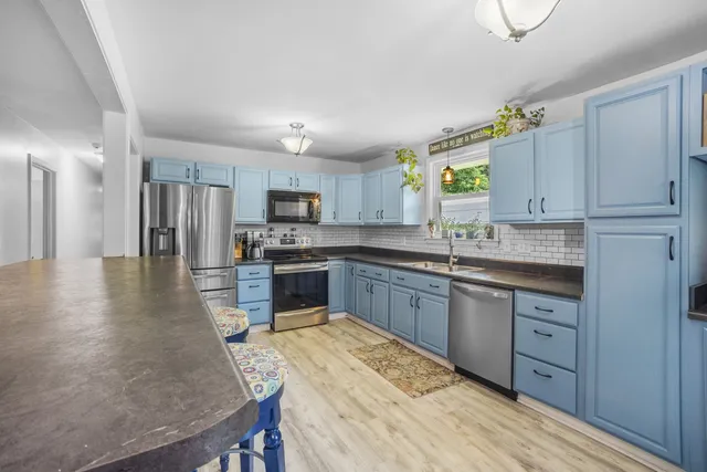 a kitchen with granite countertop a sink stainless steel appliances and cabinets