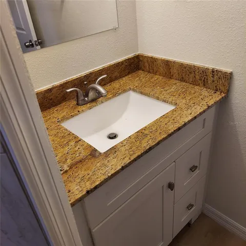 a bathroom with a granite countertop sink and white cabinets