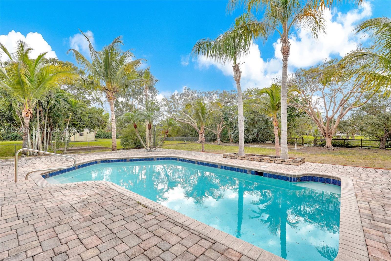 5021 Southwest 168th Avenue Southwest Ranches, FL 33331 - Photo 71 of 88 a view of a swimming pool with a lawn chairs under palm trees