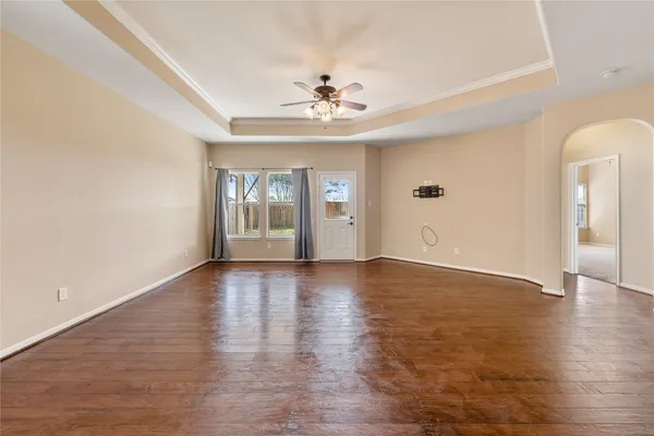 an empty room with wooden floor chandelier and windows