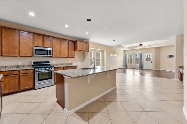 a large kitchen with granite countertop a stove a sink and a microwave