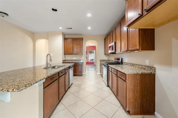 a large kitchen with stainless steel appliances granite countertop a stove a sink and a refrigerator