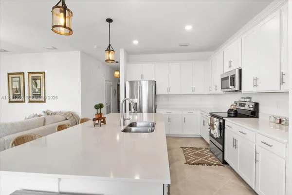 a kitchen with kitchen island granite countertop a sink a stove oven and white cabinets with wooden floor