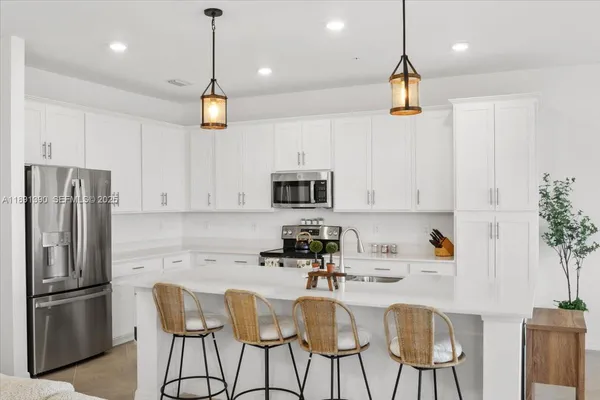 a kitchen with stainless steel appliances granite countertop a refrigerator a sink a stove a dining table and chairs