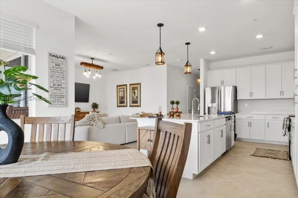 a open kitchen with stainless steel appliances granite countertop a stove a sink dishwasher a dining table and chairs with wooden floor