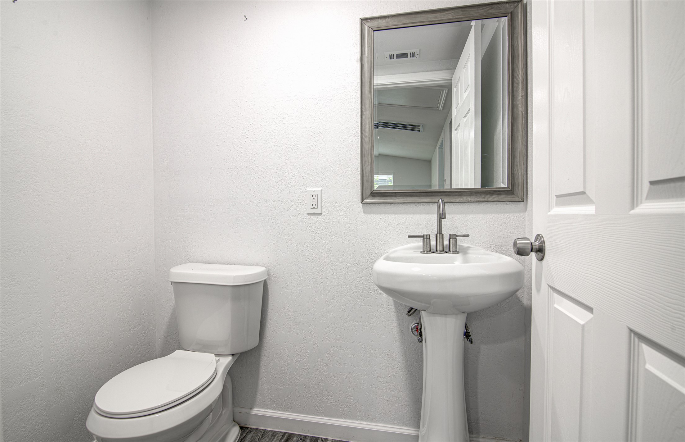 1807 San Jose Street Georgetown, TX 78626 - Photo 7 of 21 A compact powder room with a sleek pedestal sink and framed mirror.