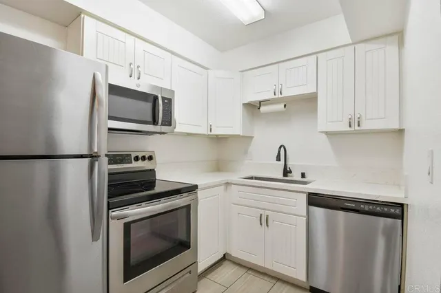 a kitchen with white cabinets stainless steel appliances and sink